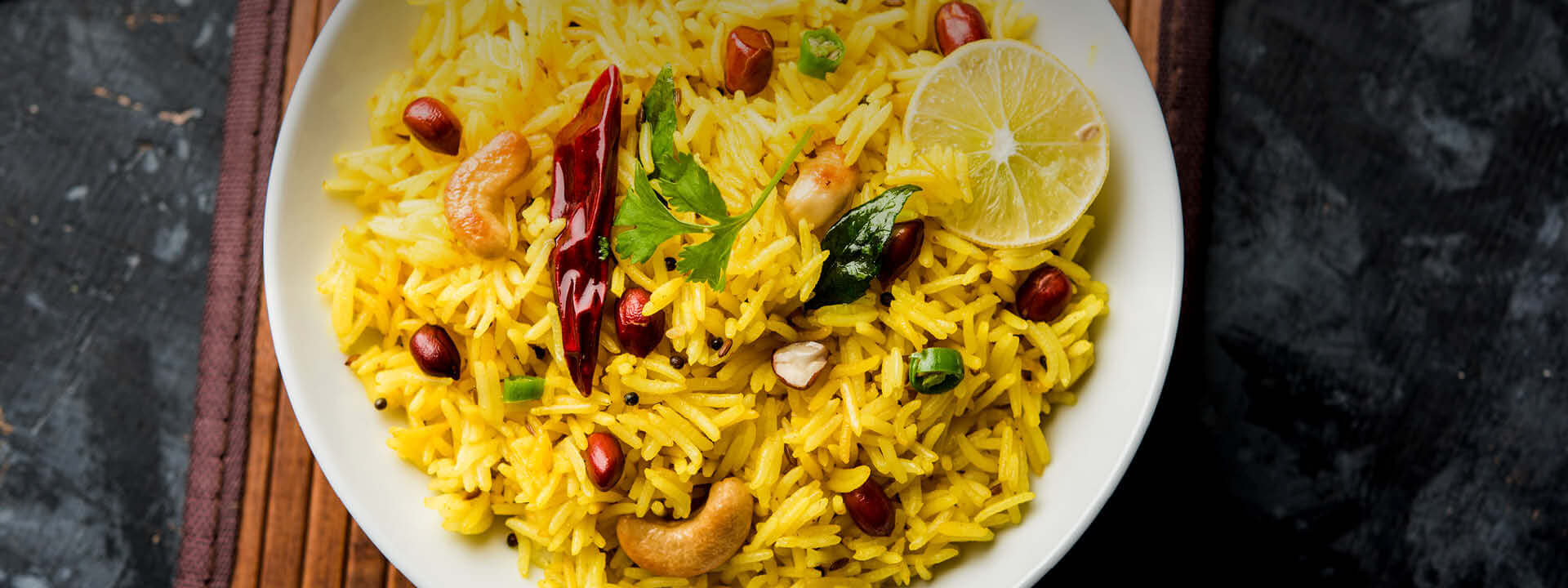 Kurkuma Verwendung - goldener Reis mit Gewürzen | EDEL KRAUT Kurkuma Reis - goldgelbes Reisgericht mit Cashews, Chili, Curryblättern und Limette in weißer Schale